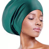 A close-up of a woman wearing a deep emerald green silicone swim cap for long hair.