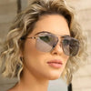 Primer plano de una mujer usando gafas de sol cuadradas de metal clásicas con lentes tintados.