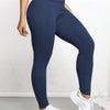 A woman wearing dark blue high-waisted sports leggings and white sneakers.