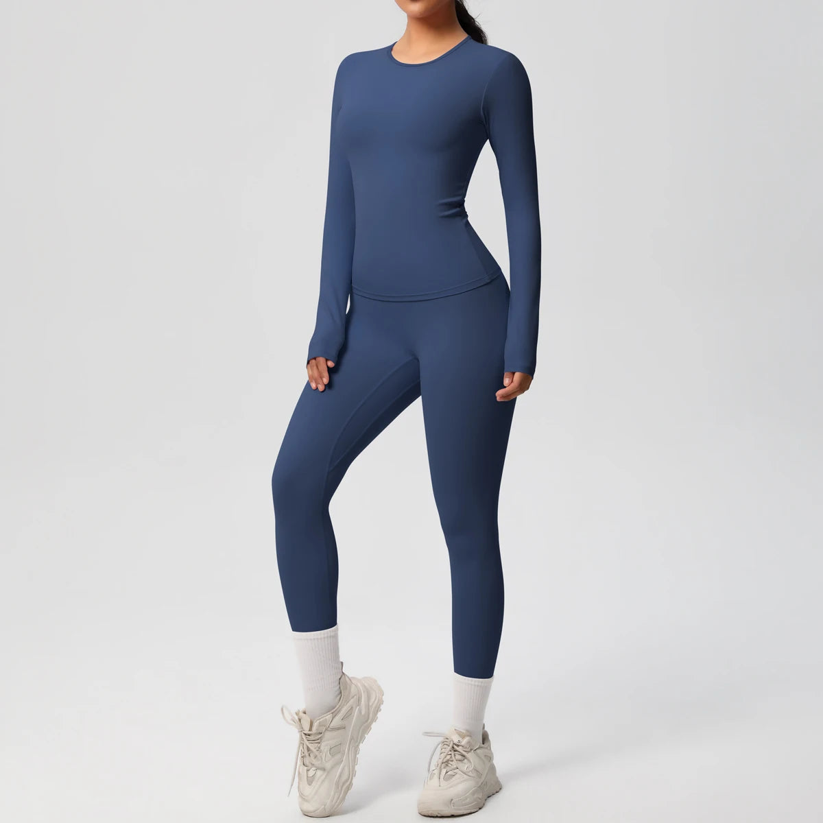 A woman wearing a navy blue performance yoga and gym set with white socks and light gray athletic shoes.