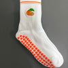 Weiße Strick-Yoga-Socken mit orangen Streifen und einem kleinen orangen Zitrusfrucht-Design an der Zehenpartie.