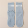 A pair of light blue Pilates grip socks with white stripes and textured soles.