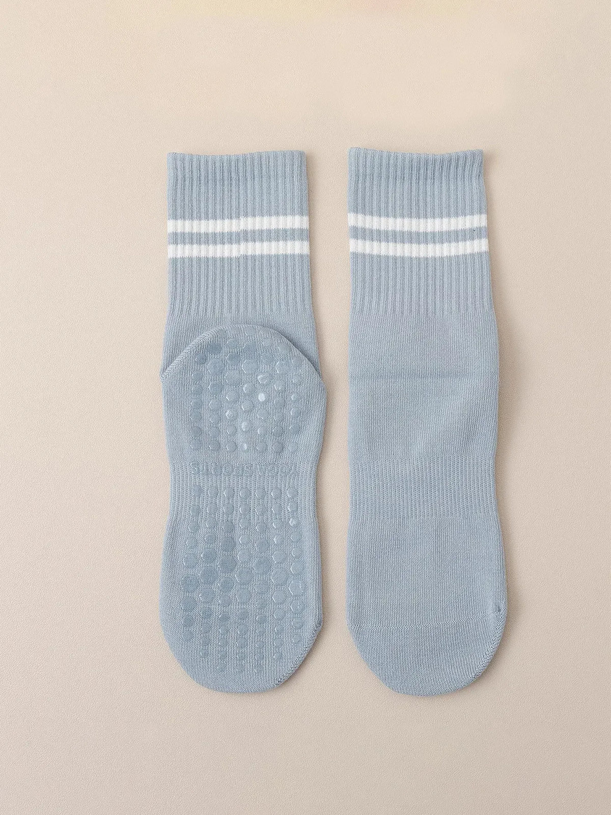 A pair of light blue Pilates grip socks with white stripes and textured soles.