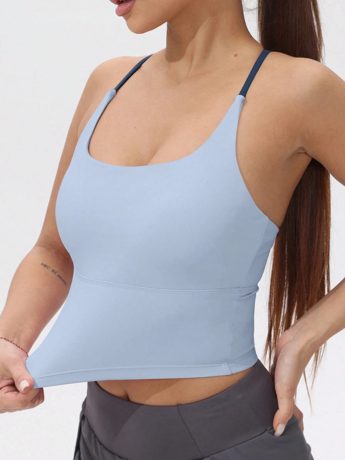 A light blue women's athletic crisscross tank top worn by a model.