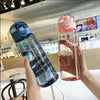 Eine Hand hält eine undurchsichtige, verschlussdichte Sportflasche mit rosa Flüssigkeit in einem hellen Innenraum.