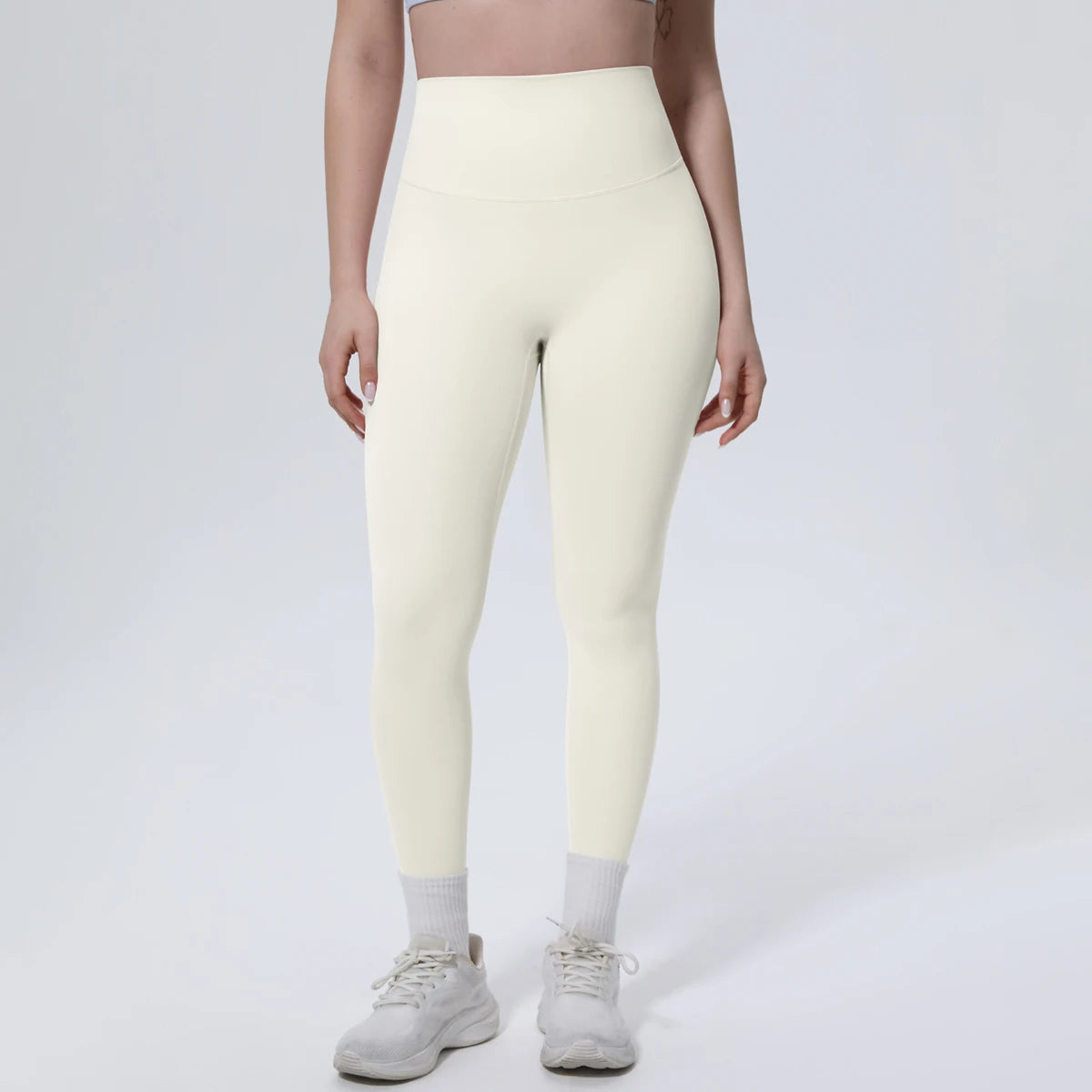 A model wearing high-waisted, light beige quick-drying yoga and fitness leggings and white socks.