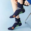 A close-up of navy blue compression running socks with neon green and orange accents being put on a person's ankle.