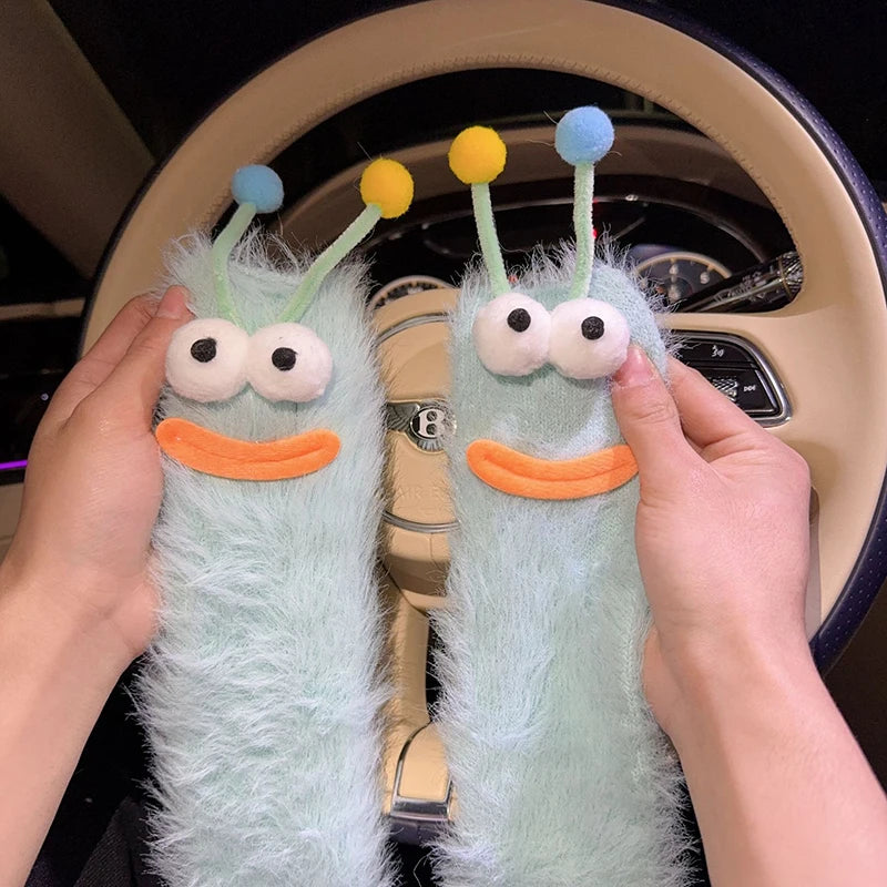 Pair of light blue knit socks shaped like cartoon characters with yellow and blue antennae
