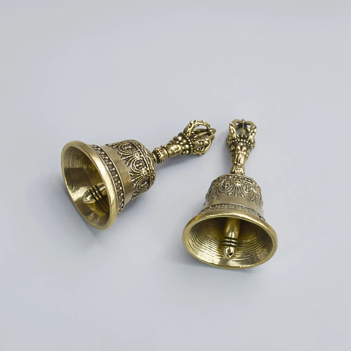 Clochette en bronze à tenir avec poignée et cloche ornée, pour décoration spirituelle ou festive.