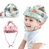 A toddler is smiling while wearing a soft adjustable safety helmet with a floral pattern.