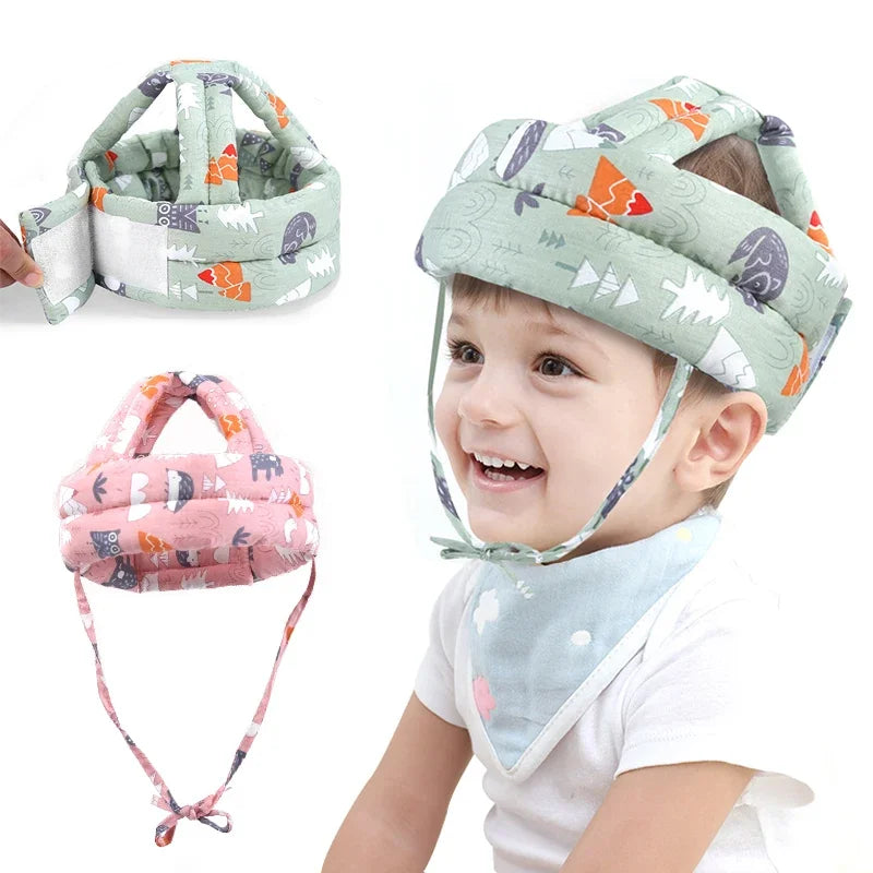 A toddler is smiling while wearing a soft adjustable safety helmet with a floral pattern.