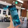 A hand holds a clear blue sports water bottle with a black cap and tea infuser.