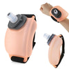 A light peach silicone wrist hydration bottle with a clear mouthpiece and black strap, shown in use on a hand.