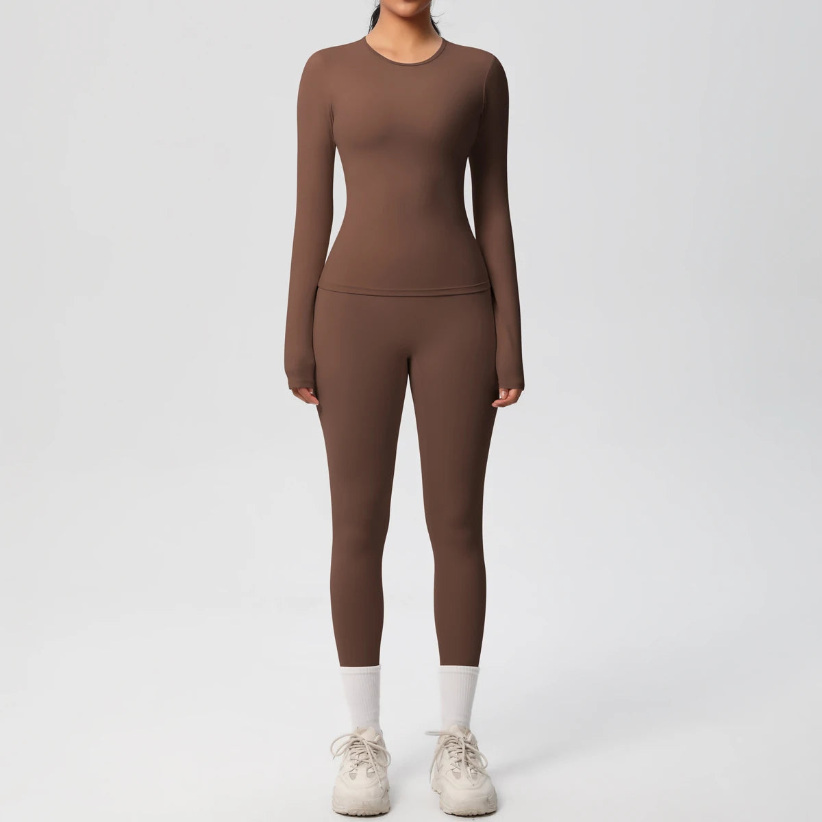 A woman wearing a long-sleeved, full-body performance yoga and gym set in a solid brown color.