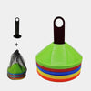 A set of colorful soccer training discs stacked in a pile next to a black cone.