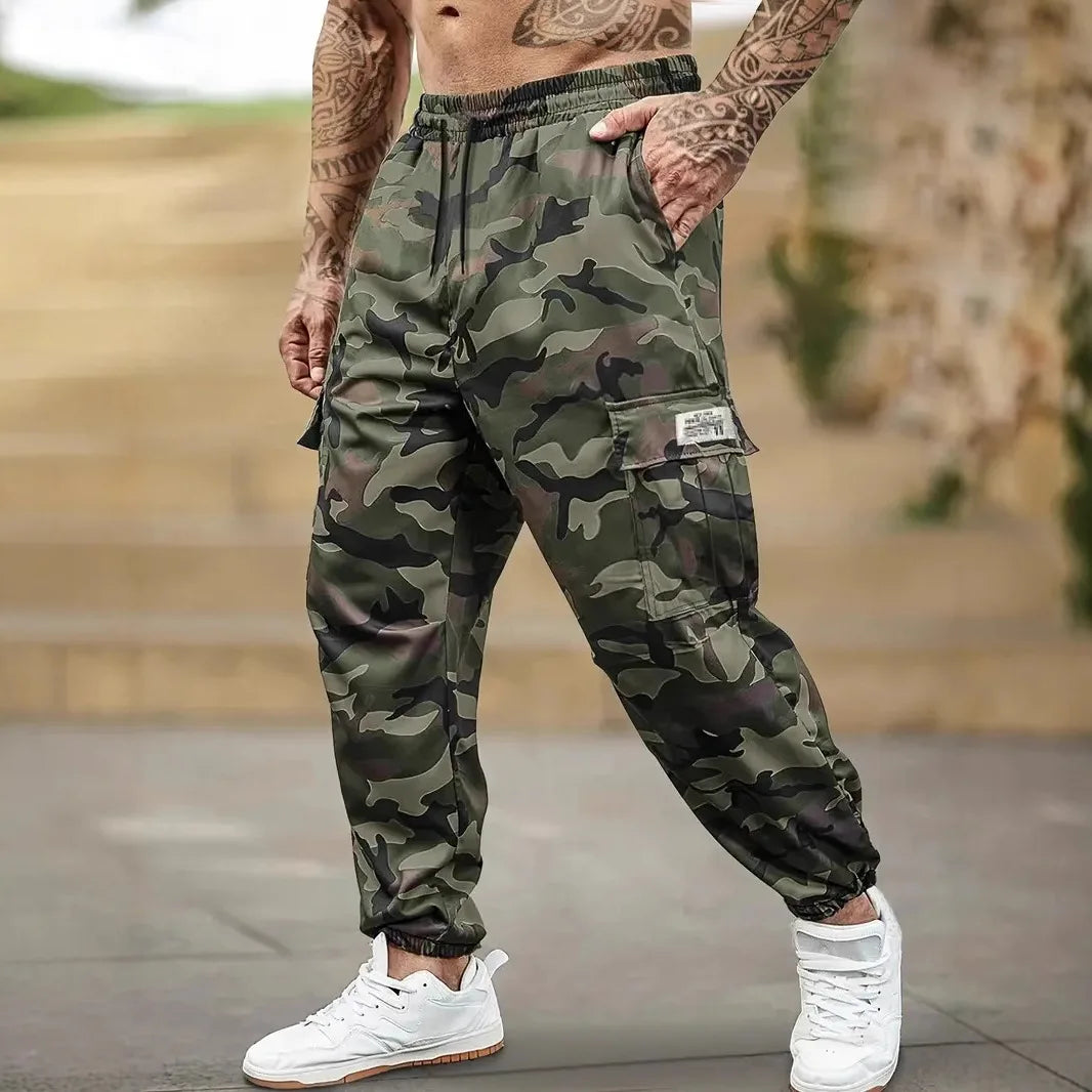 Un homme portant des pantalons cargo de camouflage avec cordon de serrage et détails de poche.
