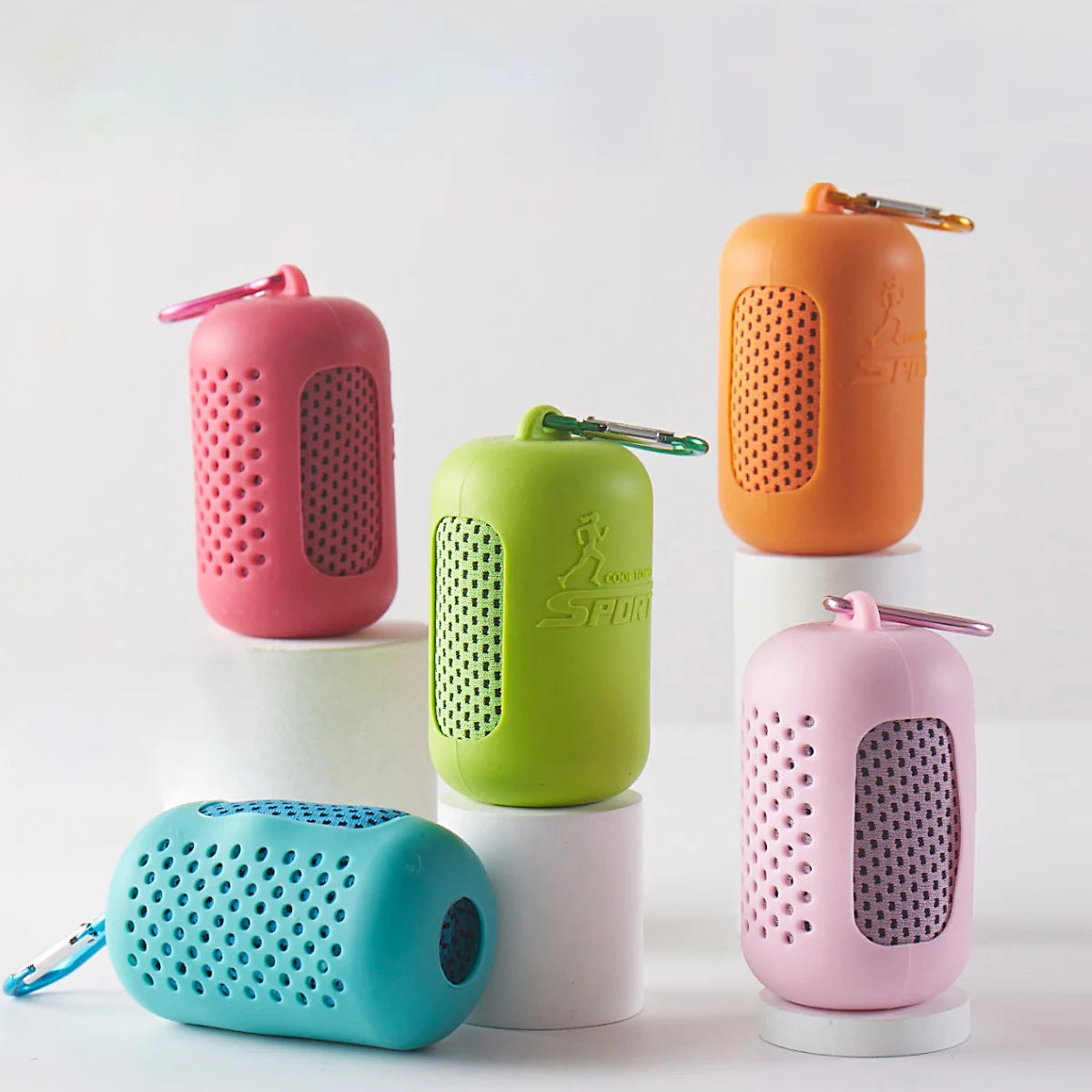 A collection of pink, green, and orange silicone cooling towels displayed on white cylindrical stands.