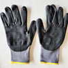 A pair of black nitrile coated safety work gloves with gray palms and yellow cuffs.