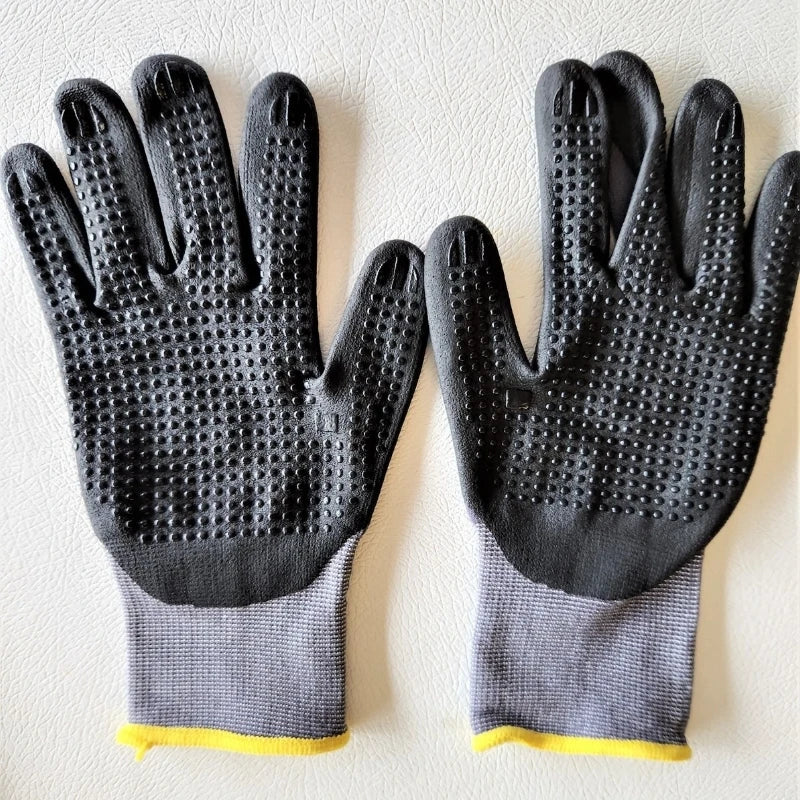 A pair of black nitrile coated safety work gloves with gray palms and yellow cuffs.