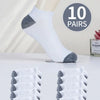 A set of ten white ankle socks with gray accents displayed next to a model's leg.