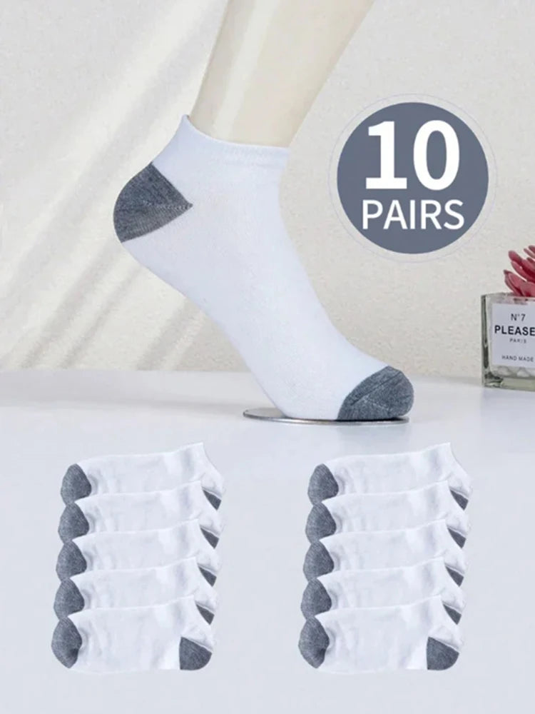 A set of ten white ankle socks with gray accents displayed next to a model's leg.
