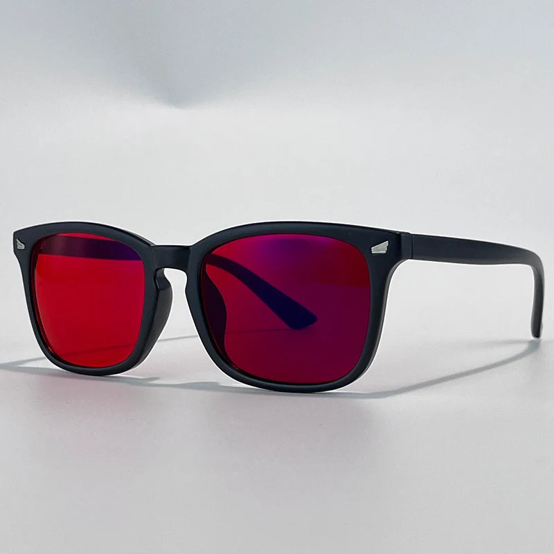 A pair of black sunglasses with vibrant red and purple mirrored lenses resting on a white surface.