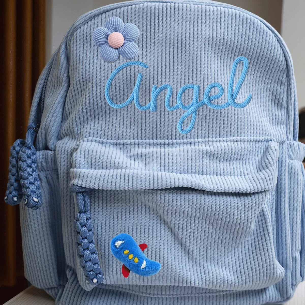 Hellblaue Cordhosen-Rucksack mit dem Namen Angel aufgestickt