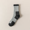 A pair of merino wool thermal hiking socks in gray and black with a ribbed cuff.