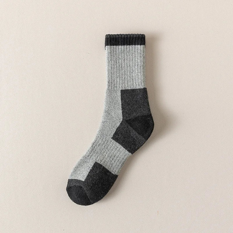 A pair of merino wool thermal hiking socks in gray and black with a ribbed cuff.