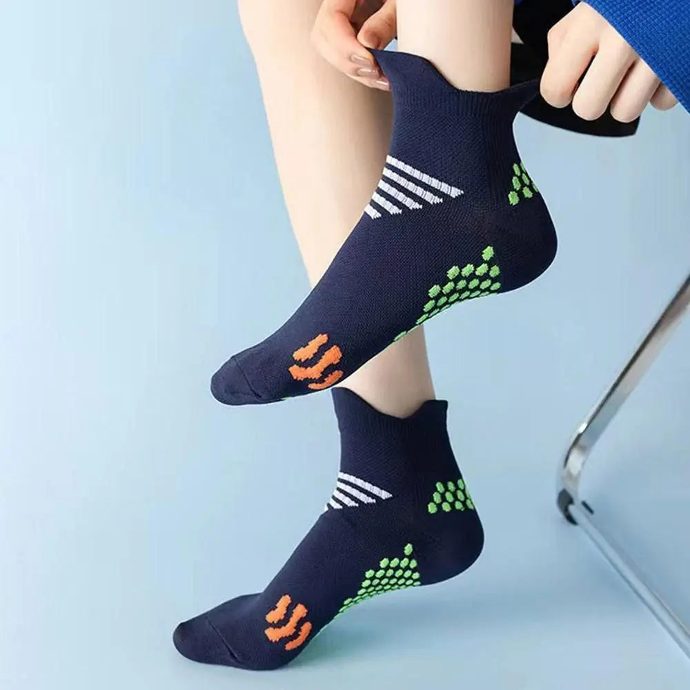 A pair of navy blue cycling and running socks with white stripes and neon green accents being put on a person's ankle.
