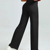 A woman models high waisted black yoga pants with white sneakers.