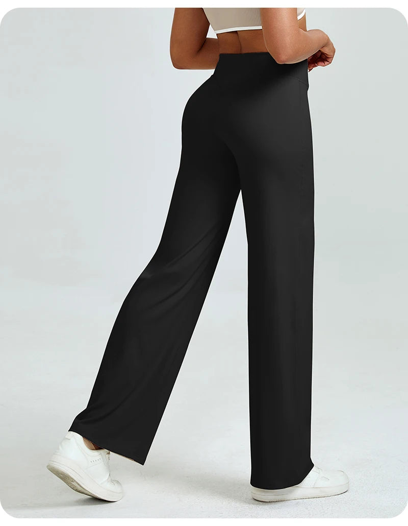 A woman models high waisted black yoga pants with white sneakers.