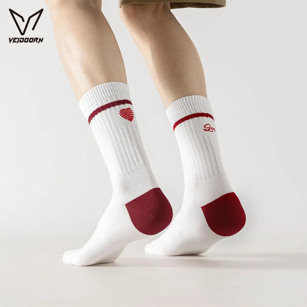 A pair of white crew socks with red accents and a logo, worn on a person's leg.