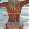 A woman shows off an elegant two-piece swimsuit set with colorful patterns on a beach.