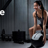 A woman in athletic wear is performing a workout exercise while holding a black exercise ball.