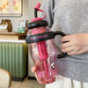 A person holds a pink glass bottle filled with ice cream in a hand.
