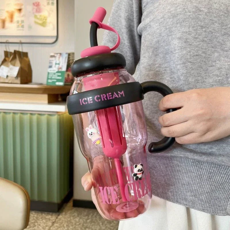 A person holds a pink glass bottle filled with ice cream in a hand.