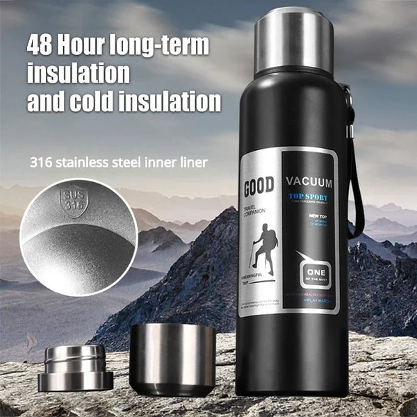 A black insulated thermos bottle with a silver lid and stainless steel inner liner is shown outdoors.