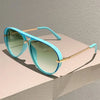 Light blue vintage pilot sunglasses with gradient lenses resting on a white surface.