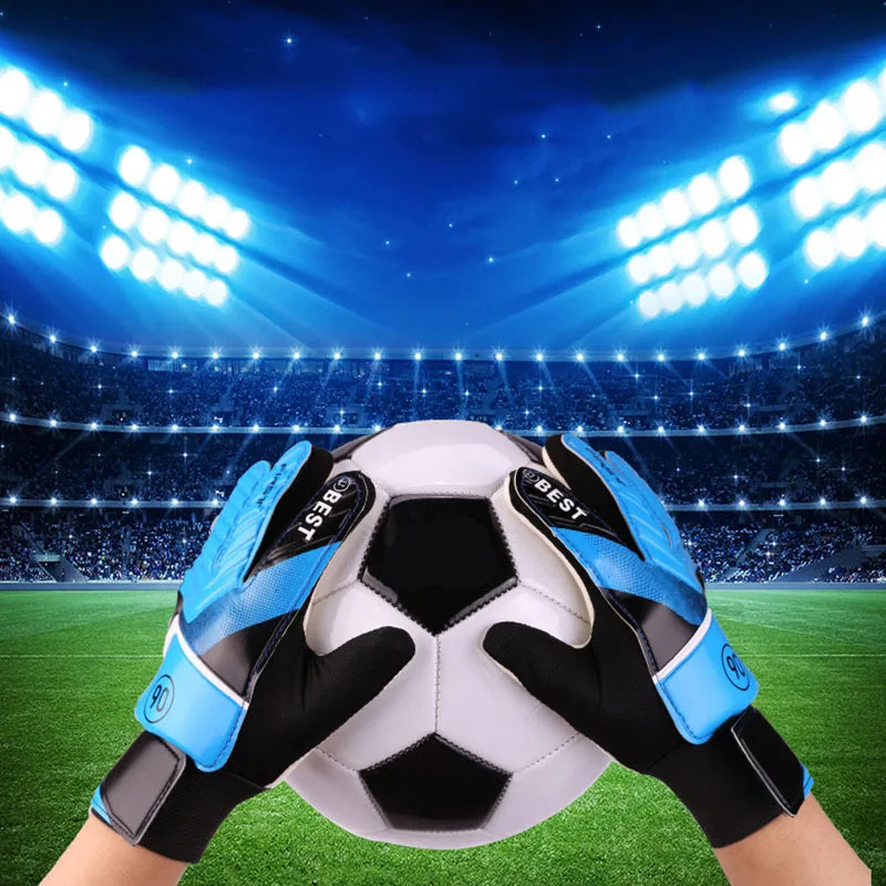 A pair of blue and black latex goalkeeper football gloves positioned over a white soccer ball on a green field under bright s