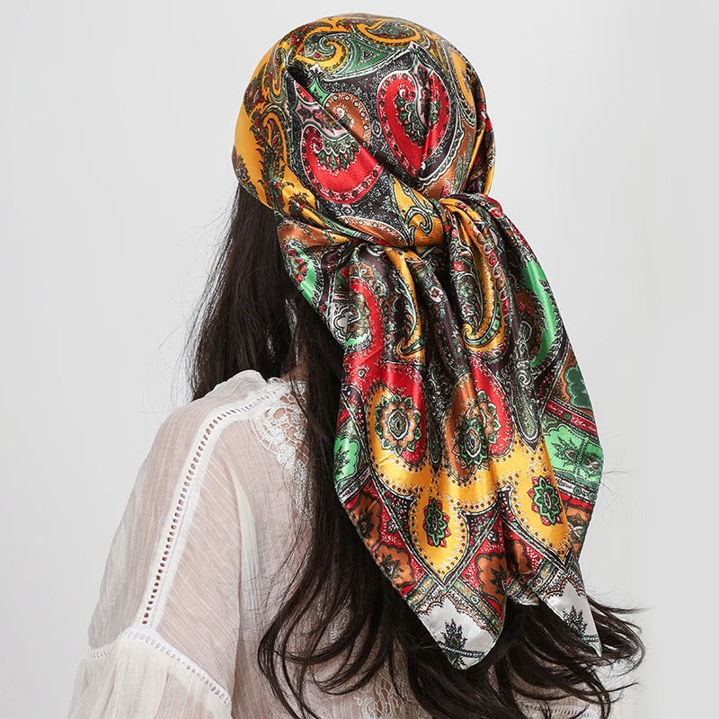 A woman wearing a colorful silk paisley shawl scarf tied around her hair, seen from the back.
