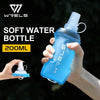 A hand holds a light blue soft water bottle with a clear cap against a dark background.