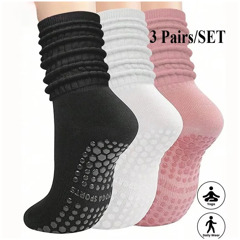 A set of three pairs of black, white, and pink silicone Pilates and yoga socks displayed together.