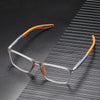 Clear-framed reading glasses with orange accents resting on a dark, striped surface.