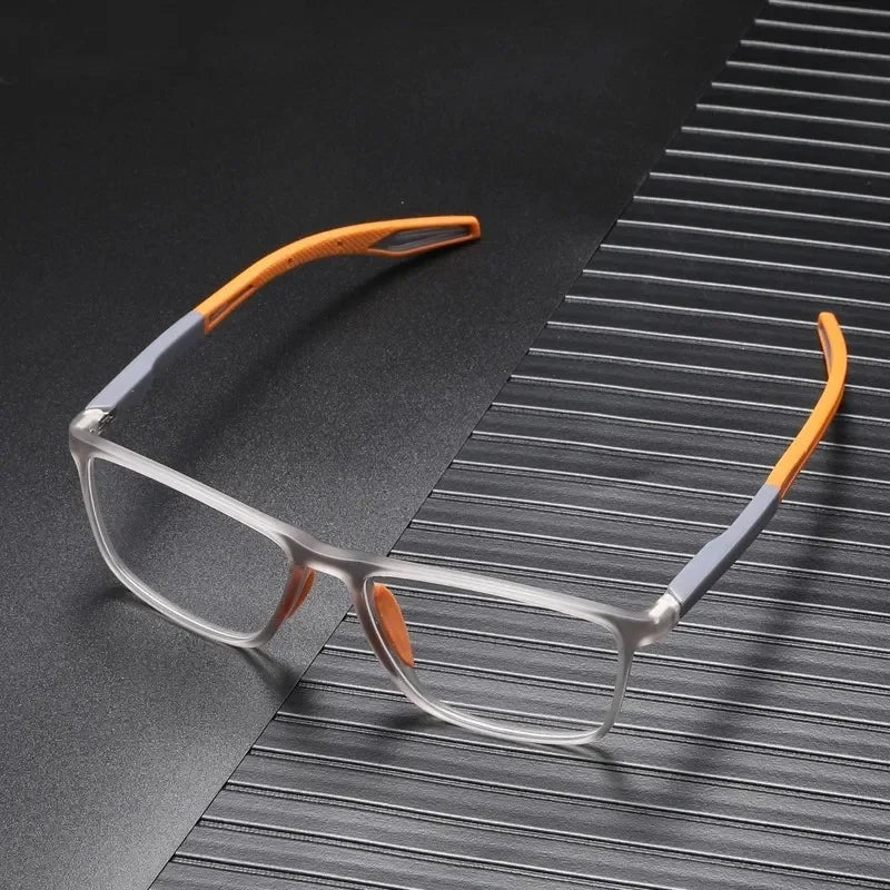Clear-framed reading glasses with orange accents resting on a dark, striped surface.