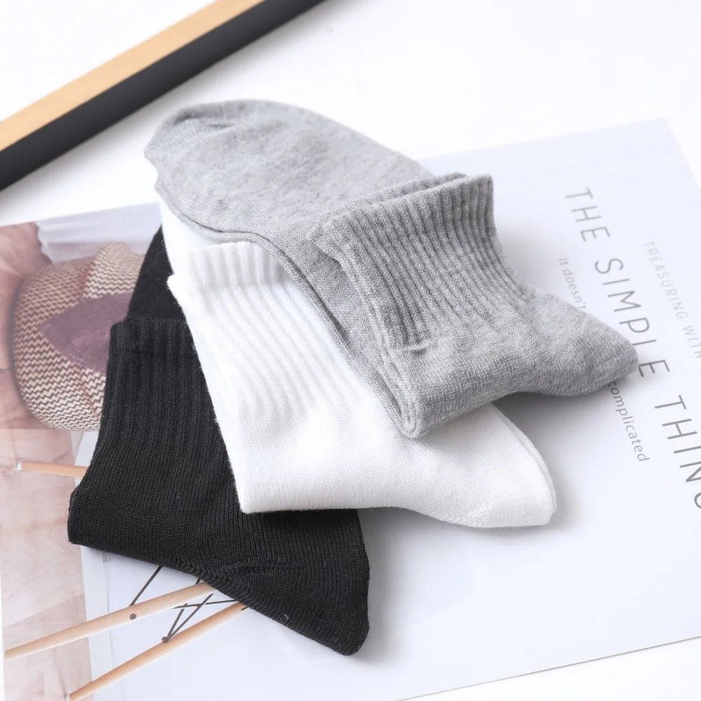 A stack of gray, white, and black men's mid-calf cotton socks displayed on a white background.