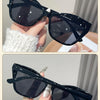 Black square cat eye sunglasses with white knit sleeve shown in a close-up shot.