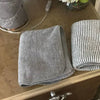 A gray soft coral fleece face towel is displayed on a wooden surface.