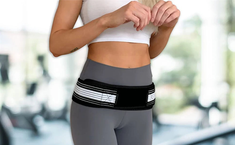 A woman wearing a gray athletic outfit with a black and white supportive hip belt for lower back relief.