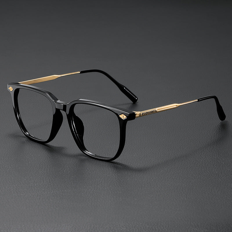 A pair of black retro anti-blue light glasses with gold accents resting on a dark surface.